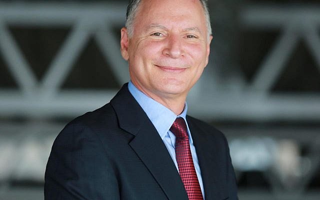 Bashar Masri smiling in a dark suit and red tie