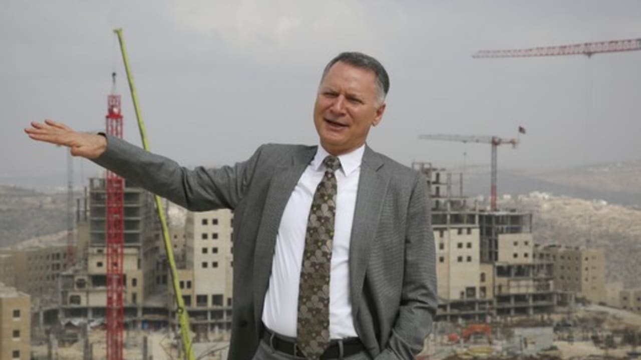 Bashar Masri gesturing toward buildings and cranes at the Rawabi City construction site